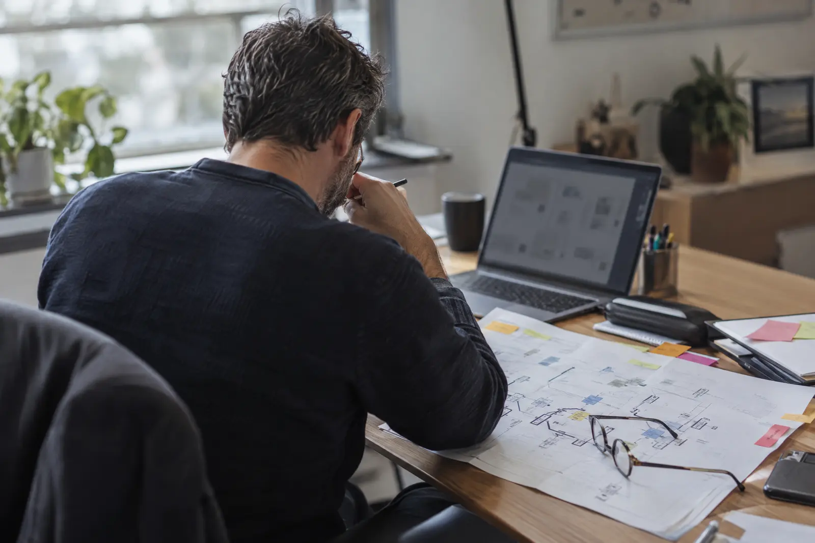 Auditeur annotant un schéma de réseau imprimé à côté d'un ordinateur portable
