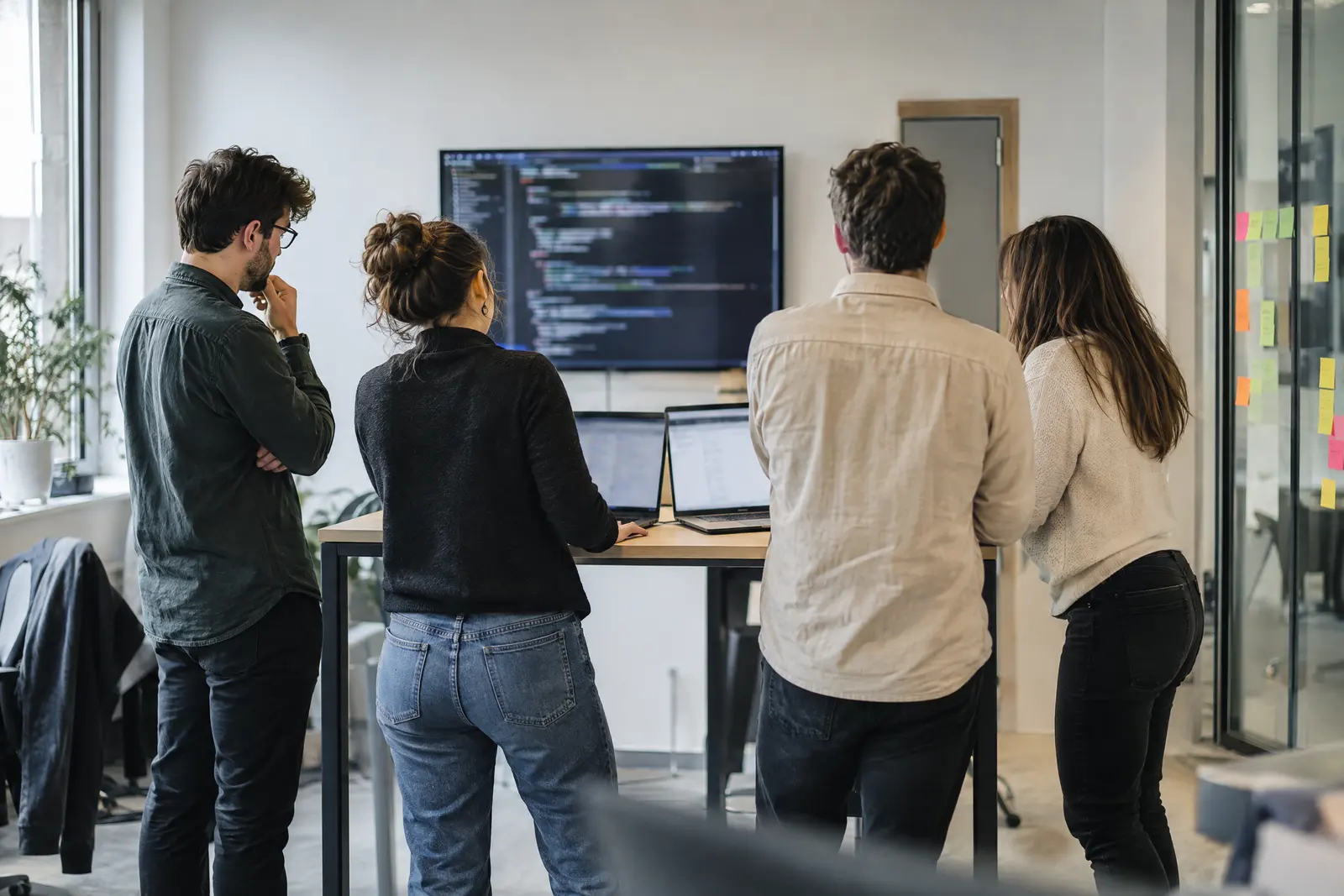 Équipe de développement devant une revue de code sur grand écran